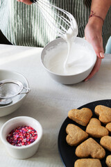 Creation of icing. Finished cookies need to be decorated. The process of making holiday cookies for Valentine's Day. Home baking with love. Vertical orientation.