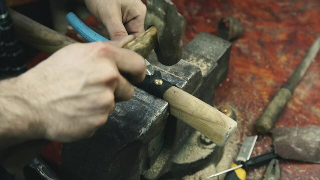 Craftsman works in workshop, close up. Creation of hatchet.