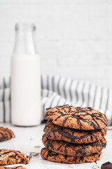 Oatmeal cookies with chocolate icing and a bottle of milk on the table. Side view.