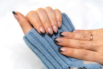 Beautiful French manicure with black contour and sequins. Well-groomed female hands with painted...