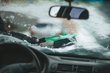 Clean snow and ice on the windshield with a brush in a snow storm.