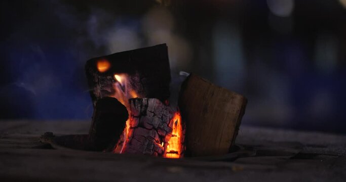 Close-up of a burning hearth. Wooden logs smolder brightly in the fire. Beautiful background with copy space. Bright flames of fire over black background, slow motion 50 fps 4k