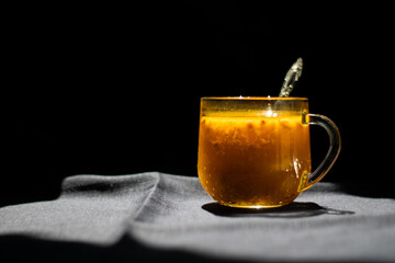 A glass of sea buckthorn tea on black background.