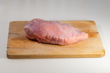 Whole turkey breasts are on a wooden board.