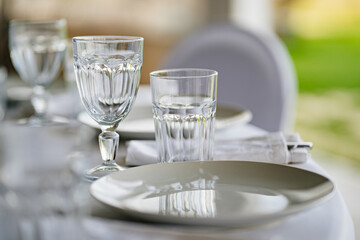 an empty white plate and glasses on the table. 