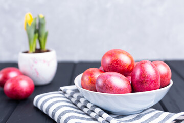 Decorated traditional Easter eggs in ceramic plate black wooden background