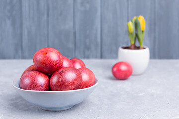 Decorated red-orange-pink Easter eggs on ceramic plate and gray marble table