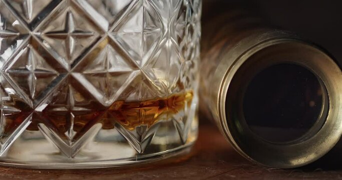 A glass of near empty Bourbon sits atop a table next to a spyglass. Fire reflecting in the depths of the lens.