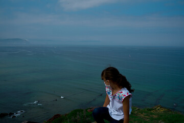 young girl watching the blue ocean from behind