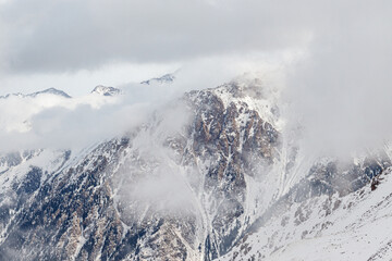 Naklejka na ściany i meble Snowy rocky mountains merging with the clouds.