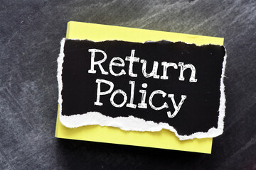 RETURN POLICY words on a black piece of paper.