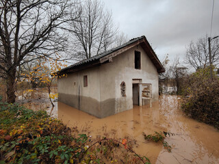 Torrential rain causes flash floods in residential areas. Destroyed house surrounded by water. 
