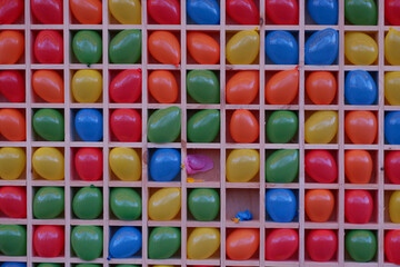 Air darts. Inflatable multi-colored balls in cells for playing darts. Multi-colored balloons on the board for playing darts. Colorful background, rainbow colors.
