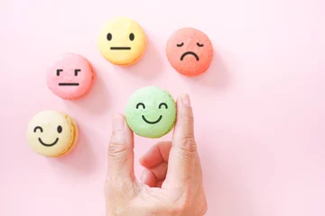 Foto op Canvas hand kies emotiegezicht op groene macarons, goede feedbackbeoordeling en positieve klantbeoordeling, ervaring, tevredenheidsonderzoek, beoordeling van de geestelijke gezondheid, kinderwelzijn, wereldconcept voor geestelijke gezondheid © Ratana21