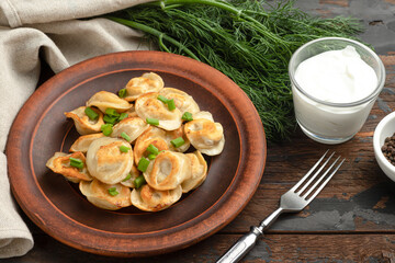 fried dumplings with pepper, sour cream, with appliances on a wooden background side view, Russian national food