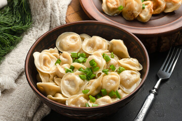 fried and boiled dumplings on a black background, side view, with greens, Russian national food