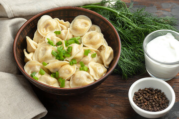 Boiled dumplings, with herbs, sour cream, on a wooden background, Russian national food