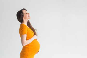 Young pregnant woman in yellow dress on white background