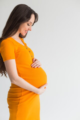 Young pregnant woman in yellow dress on white background