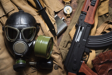 Airsoft weapon and gas mask flat lay background.
