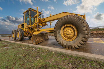 A motor grader at a road construction site - obrazy, fototapety, plakaty
