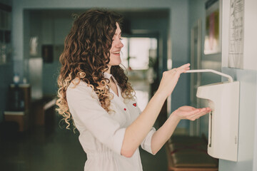 Woman doctor disinfecting her hands in the hospital before receiving a patient