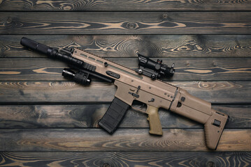Airsoft rifle on the wooden table flat lay background.