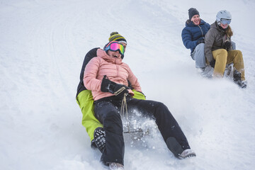 Crazy happy friends having fun with sledding on snow high mountains - Focus on right girl