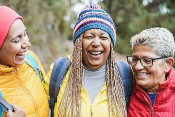 Portrait of multiracial female friends having fun during trekking day in mountain forest - Focus on...