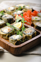 Close-up Hot sushi rolls. Baked rolls with shrimps on a wooden utensils. Bamboo chopsticks and soy sauce.