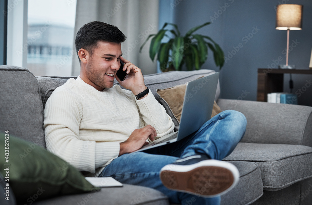 Poster Clocking into work from the couch. Shot of a young man using a laptop and smartphone while working from home.