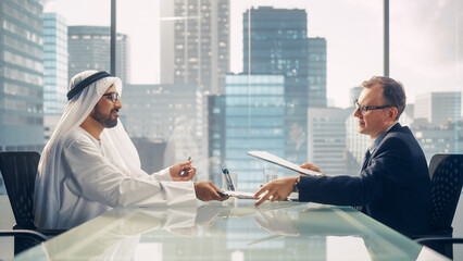 Two Businessmen with Different Nationalities Sitting in Office and Signing Contract. Arab Business...