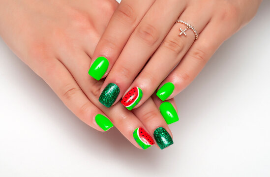 Bright neon green manicure with painted watermelons and green glitter on short square nails close-up on a white background.