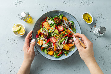 Woman eating fresh colorful spring vegetable salad - healthy organic vegan lunch.