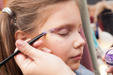 Festive face makeup for a little girl, glitter on