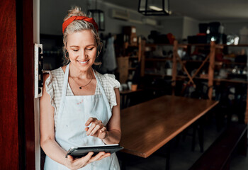 Checking future designs. Cropped shot of an attractive mature woman standing alone and using a tablet in her pottery workshop.