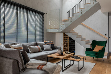 Stylish composition of living room interior with corner grey sofa, green velvet armchair, coffee table, wooden floor,  design furniture and personal accessories. Modern home decor. Template.