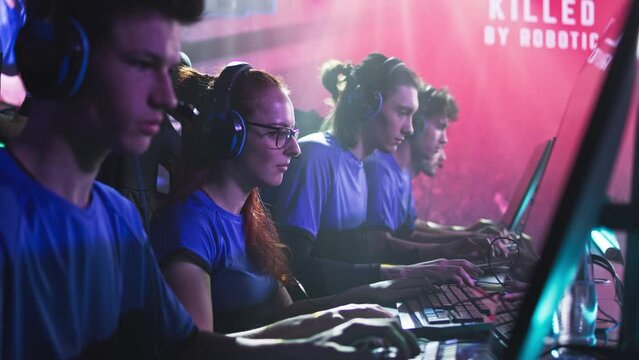 Team of male and female esportsman gamers playing shooter on computers during professional gaming tournament battle