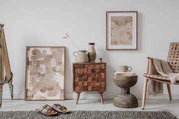 Elegant comosition of masculine room decor with small wooden cupboard, two mockup paintings and vintage accessories. Home staging. Template. Copy space..