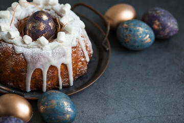 Easter card with a copy of the place for the text. Purple, blue and golden eggs with a cake on a dark background. The purple hue trend of 2022 is very peri. Natural dye karkade tea. Top view.