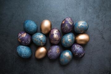 Easter card with a copy of the place for the text. Purple, blue and golden eggs on a dark background. The trend of 2022 purple shade is very peri. Natural dye karkade tea. Top view.