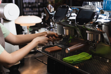 Fototapeta na wymiar Cropped view of barista working with coffee machine near rags in cafe.