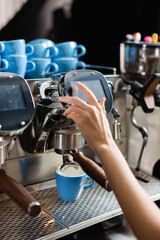 Cropped view of barista using coffee machine near cups in cafe.