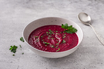 Beetroot soup puree with herbs and spices on gray background. Delicious homemade food