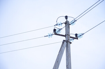 An electric pole with emergency wires on the background of a cloudy winter sky.
