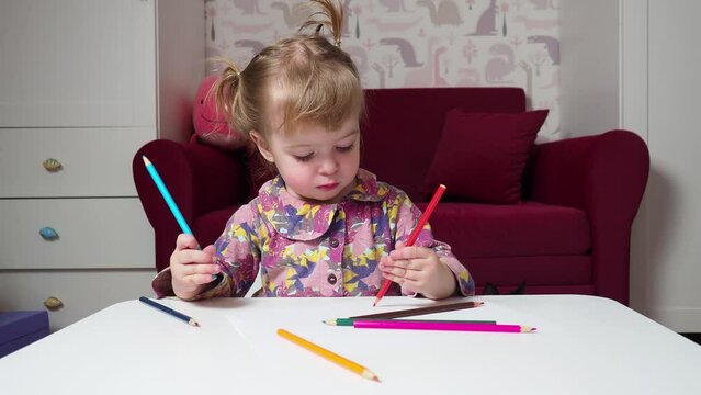 little girl learning to draw with colored pencils
