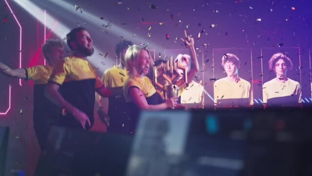 Professional esport team of gamers winners with golden cup jumping and hugging each other while celebrating victory in esports championship