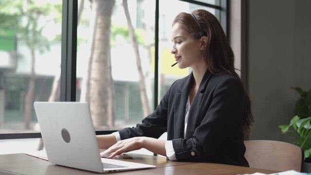 latin business woman using headset talking to customer online service . hispanic Female customer support operator in Call center agent service . listen take notes and typing on laptop keyboard
