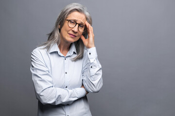 Tired mature female employee feel bored and tired. Upset senior gray-haired woman looking at the...