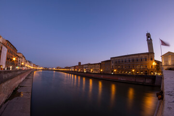 Fototapeta premium Italy Tuscany Pisa along the Arno River at sunset, street lamps lit on the promenade